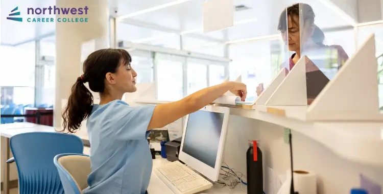 A Medical Assistant assists a patient at the reception desk in a bright, modern healthcare setting.