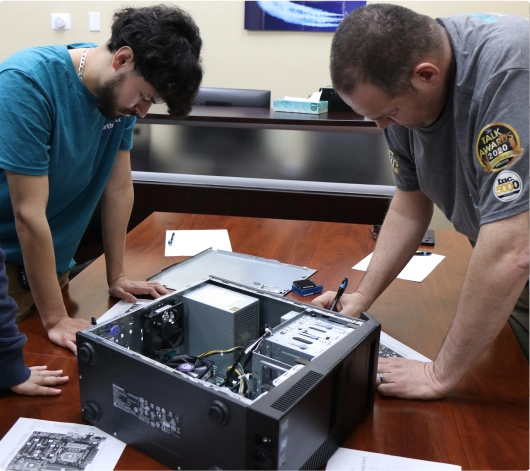 Two individuals work together on a computer, engaged in hands-on learning for the IT Technician program.