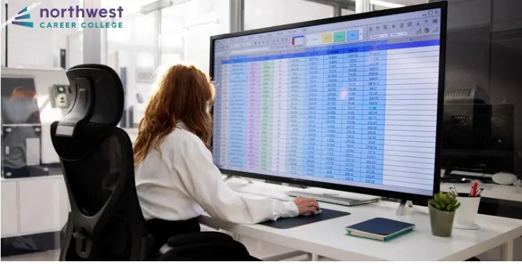 A woman analyzes data on a large screen, focusing on Medical Billing and Coding spreadsheets in a modern office.