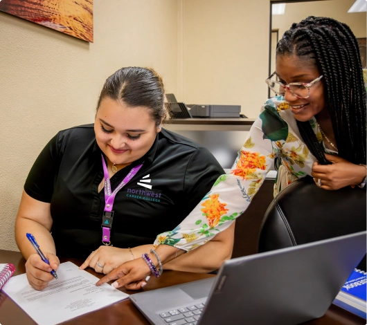 Two women collaborate on documents in an office, highlighting the paralegal studies program in Las Vegas.