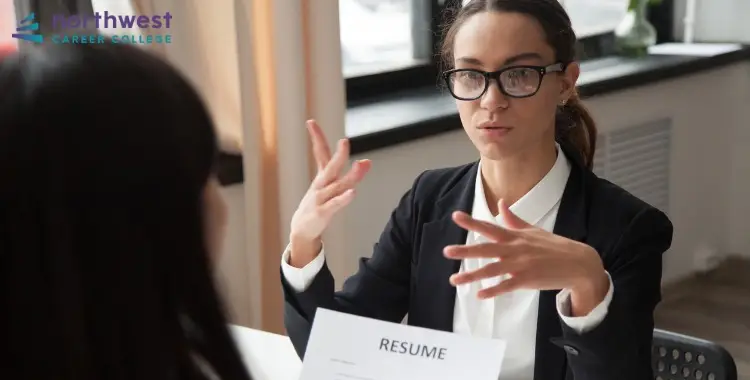 A woman in a suit discusses Paralegal Interview Questions during an interview, with a resume on the table.