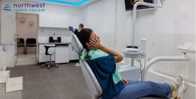 A dental assistant looks stressed in a clinic, highlighting issues of burnout among dental assistants.