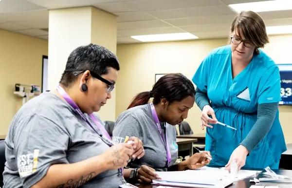 Two students work with an instructor in a classroom setting, focusing on medical assistant certification in Las Vegas.