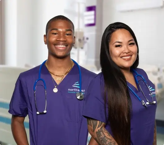 Two smiling medical assistants in scrubs, embodying the mission and goals of compassionate healthcare.