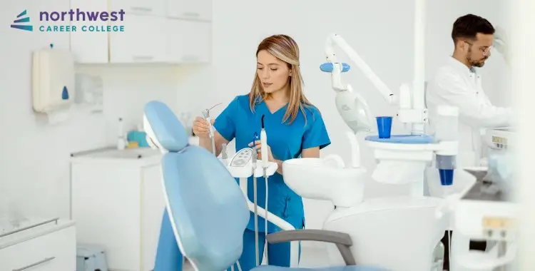 A Dental Administrative Assistant prepares tools in a modern dental office while a dentist works in the background.