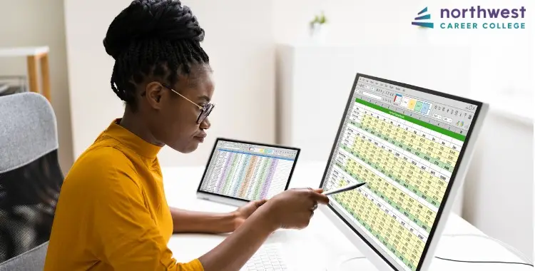 A woman analyzes data on dual monitors, illustrating work environments for a Medical Billing & Coding Specialist.