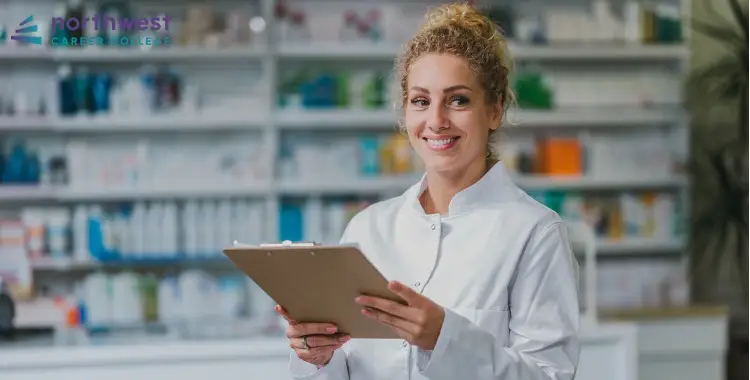 Smiling pharmacist holding a clipboard in a pharmacy, illustrating the Difference Between PTCB and CPhT.