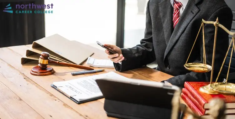 A Litigation Paralegal reviews documents and uses a smartphone at a desk with legal tools and books.