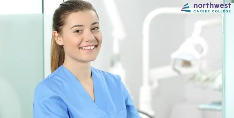 Smiling woman in scrubs at a dental office, representing Dental Administrative Assistants at Northwest Career College.