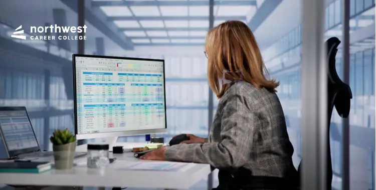 A woman works on a computer with spreadsheets, exploring How Long Does It Take to Complete a Medical Billing and Coding.