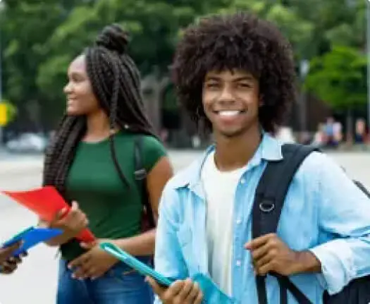 Two students outdoors, one smiling with a backpack and folders, the other looking away, both in casual attire.