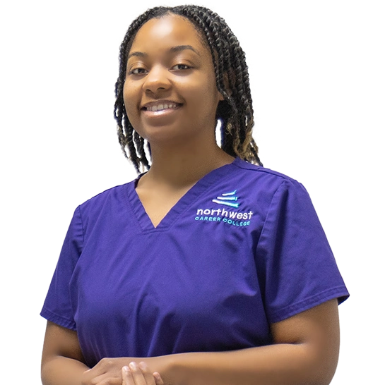 Smiling woman in a purple scrubs top with northwest career college logo, standing with arms crossed.